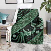Green batik pattern blanket draped on gray sofa, bird and floral motifs