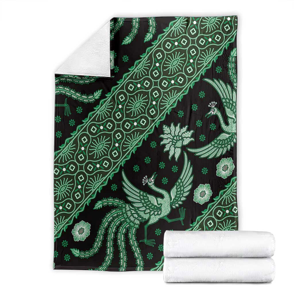 Green batik pattern blanket with bird and floral motifs, folded over white backing