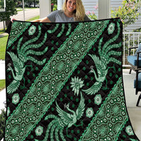 Green and black batik quilt close-up with repeating diamond, floral, and bird motifs