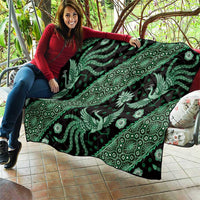 Green and black batik quilt draped on couch, featuring ornate bird and floral design