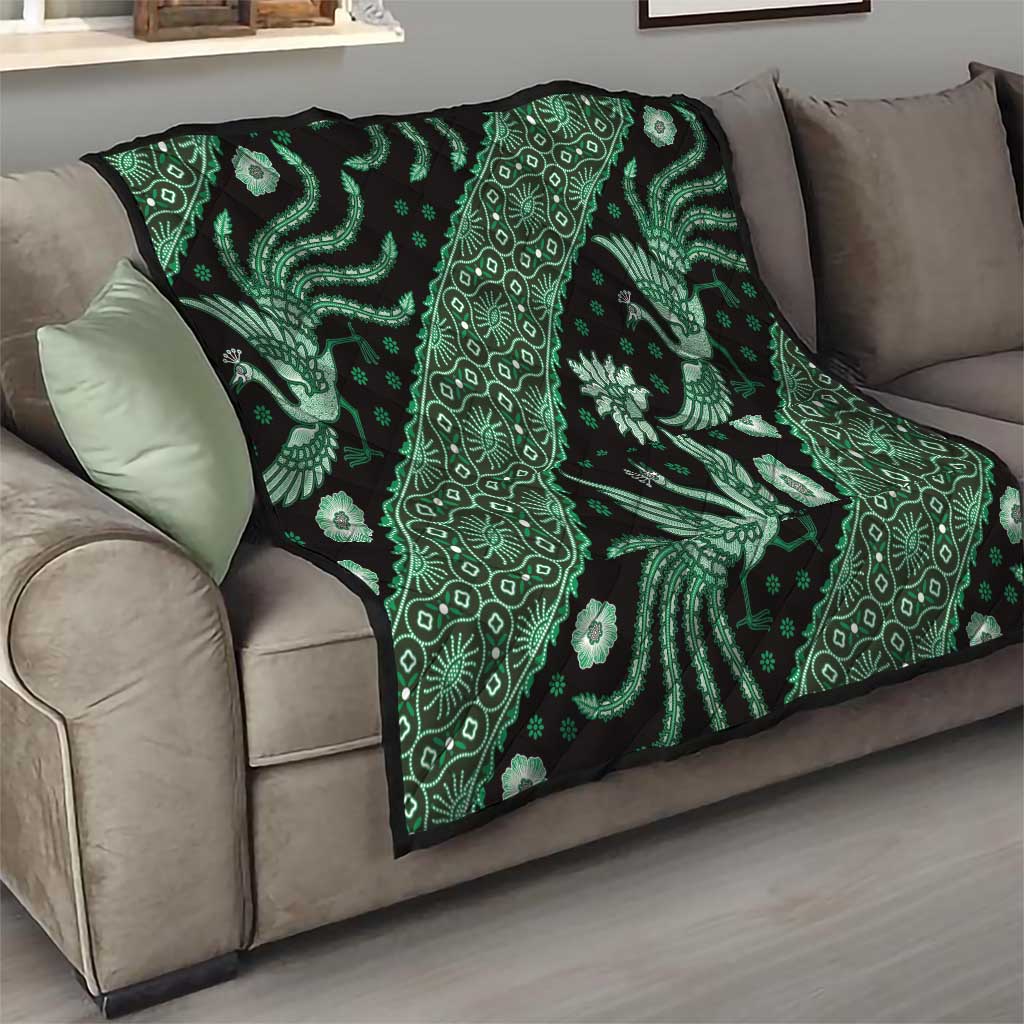 Green and black batik quilt on sofa with bright floral and bird motifs