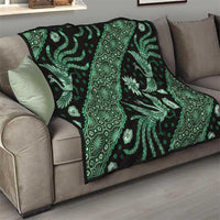 Green and black batik quilt on sofa with bright floral and bird motifs