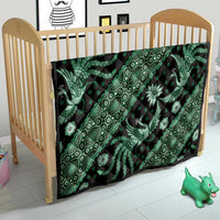 Green and black batik quilt over baby bed, with bird, floral, and diamond patterns