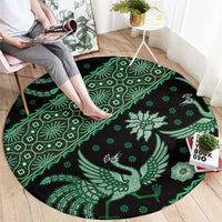 Green and black round batik-style carpet with bird, leaf, and floral motifs
