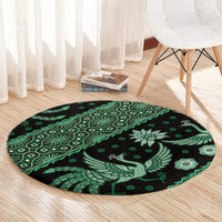 Round green and black batik-style rug with bird and geometric pattern band