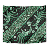 Green batik tapestry featuring repeating bird, flower, and geometric motifs on dark background.