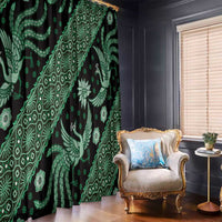 Green batik-pattern window curtain close-up with bird and floral shapes on dark fabric