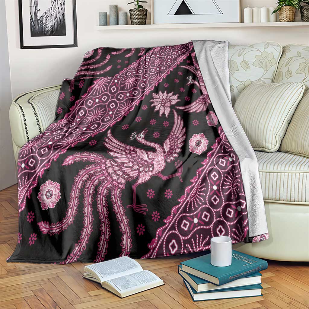 Batik pattern blanket draped over sofa, showing pink bird and floral design on dark base