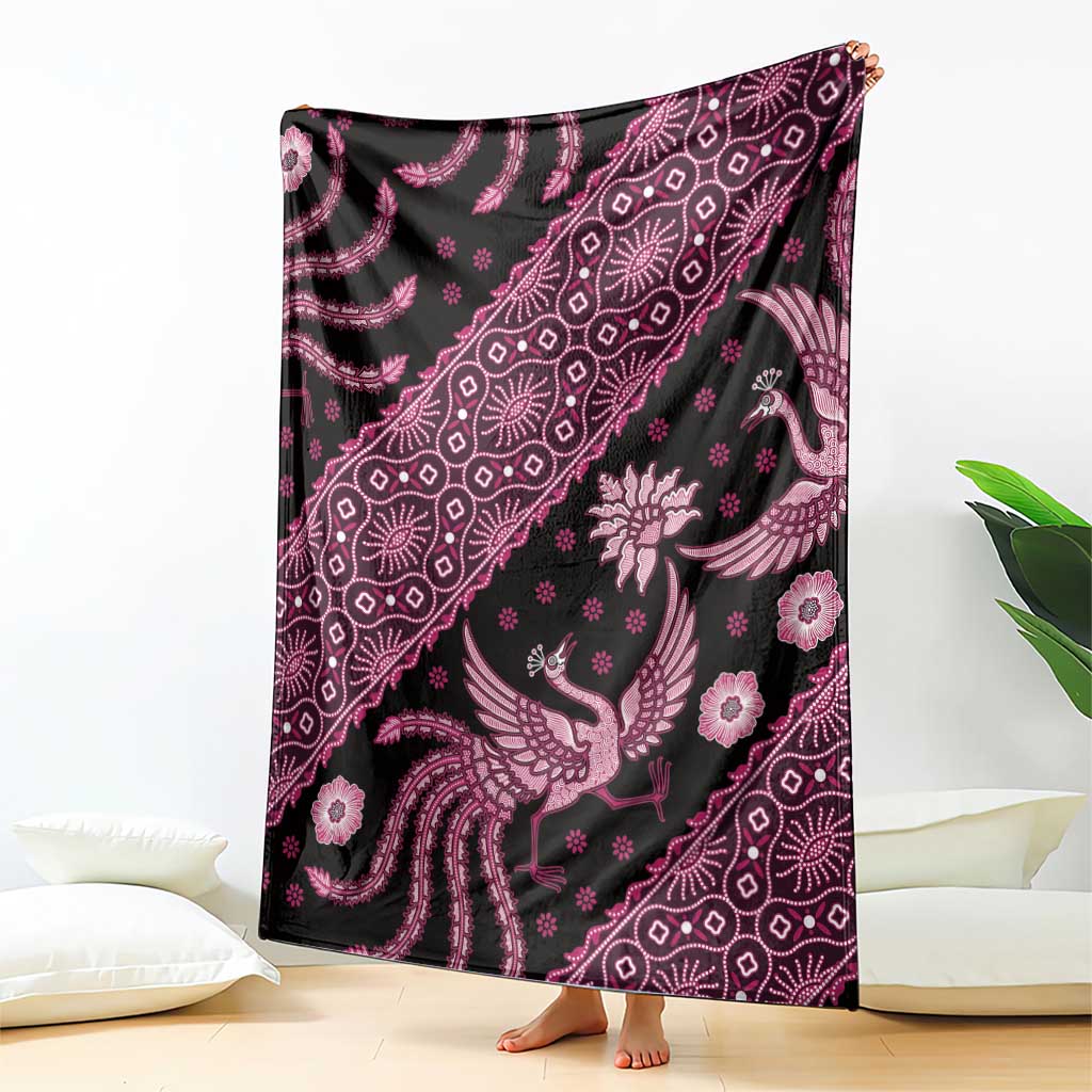 Batik pattern blanket laid flat, pink bird and floral motifs with ornate detailing on dark fabric