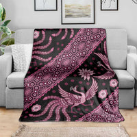 Pink batik pattern blanket on gray couch, featuring bird and flower motifs on dark background