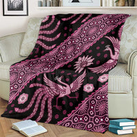 Batik pattern blanket on striped armchair, pink bird and floral motifs across dark fabric