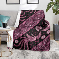 Batik pattern blanket folded on floor, pink bird and floral motifs on dark fabric with fringe