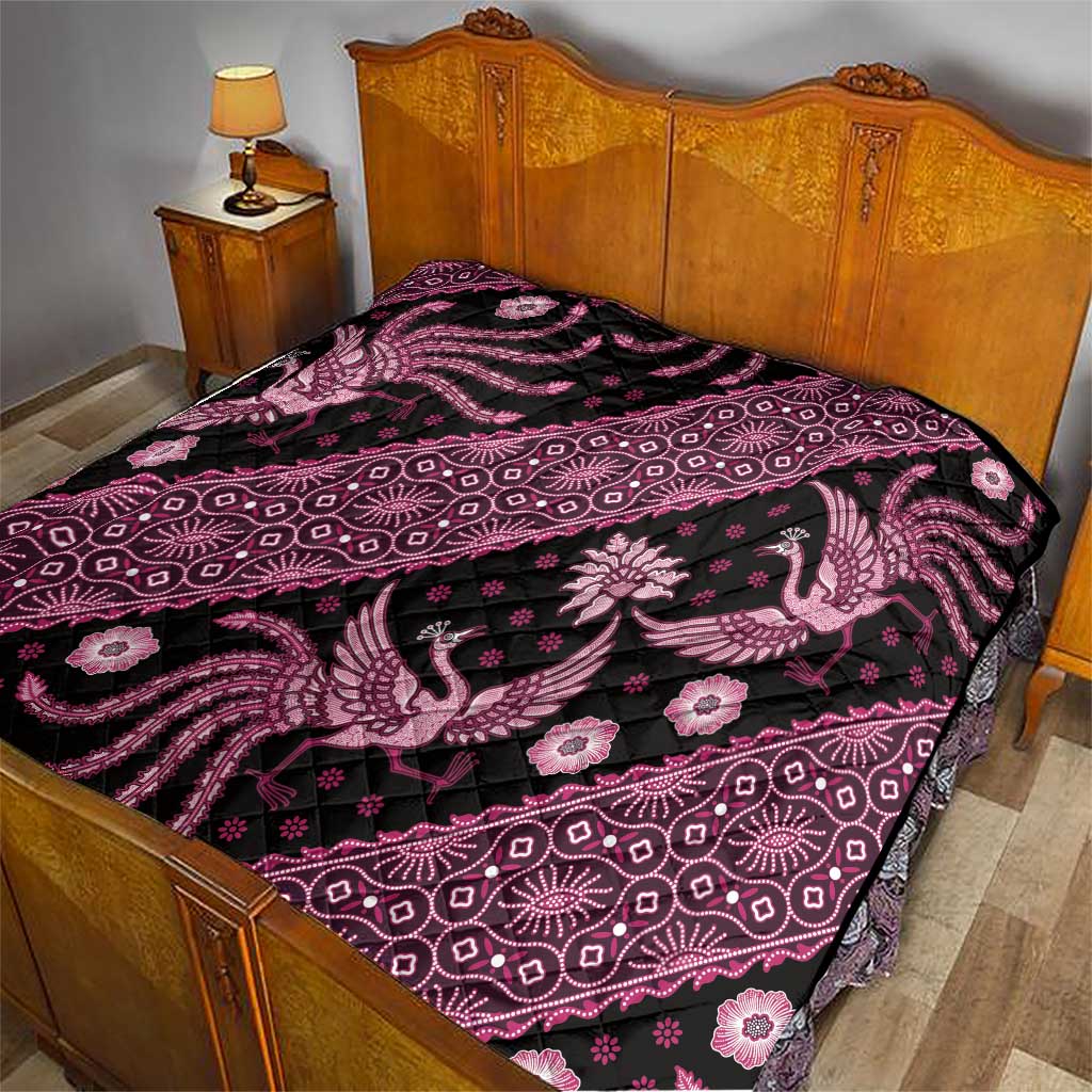 Pink and black batik-pattern quilt on a wooden bed, peacock and floral motifs.