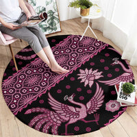 Pink round batik-pattern rug with bird and flower designs on a dark base.