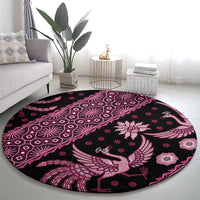 Round batik-pattern area rug in pink and dark with bird, flower, and geometric motifs.