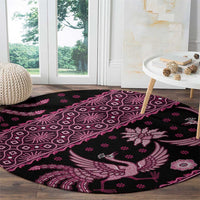 Pink and dark round batik-pattern rug with floral and bird motifs on dark base.