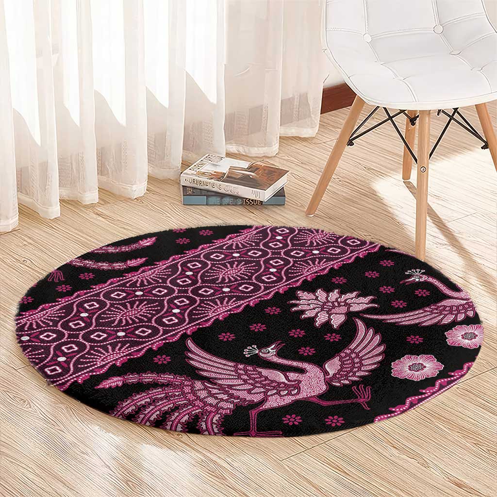Pink round batik-pattern rug with central bird and floral motifs on dark base.