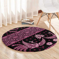 Pink round batik-pattern rug with central bird and floral motifs on dark base.