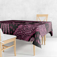 Batik tablecloth draped over table, dark fabric with pink ornamental batik motifs.