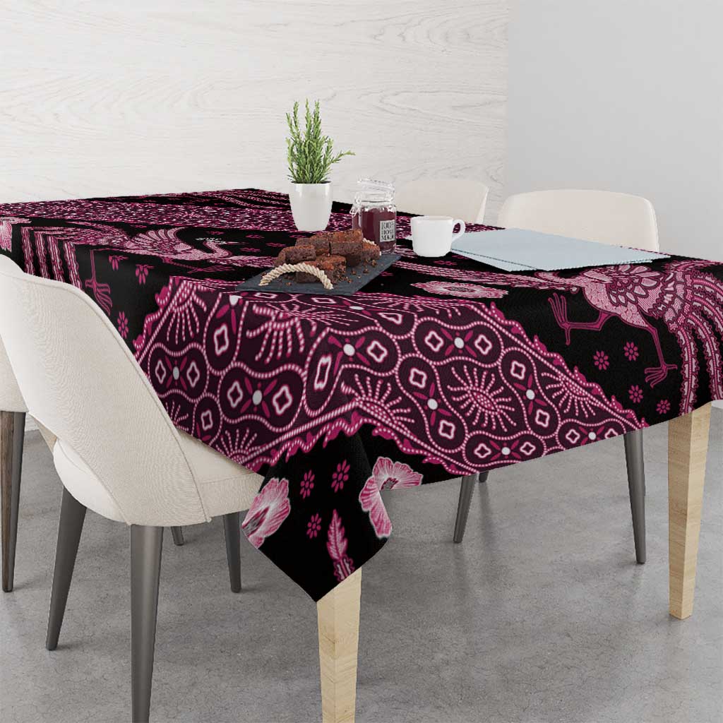 Batik tablecloth with dark base and pink motif print, folded on dining table edge.