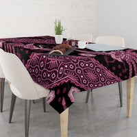Batik tablecloth with dark base and pink motif print, folded on dining table edge.