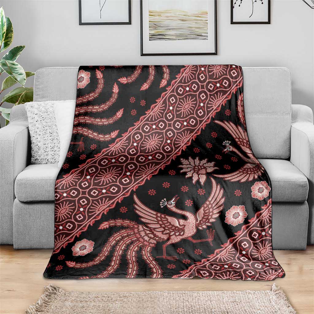 Batik-pattern blanket draped on sofa, dark ground with red bird and floral designs