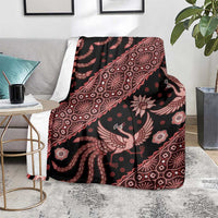 Batik-pattern blanket folded on couch, dark base with red bird and floral pattern