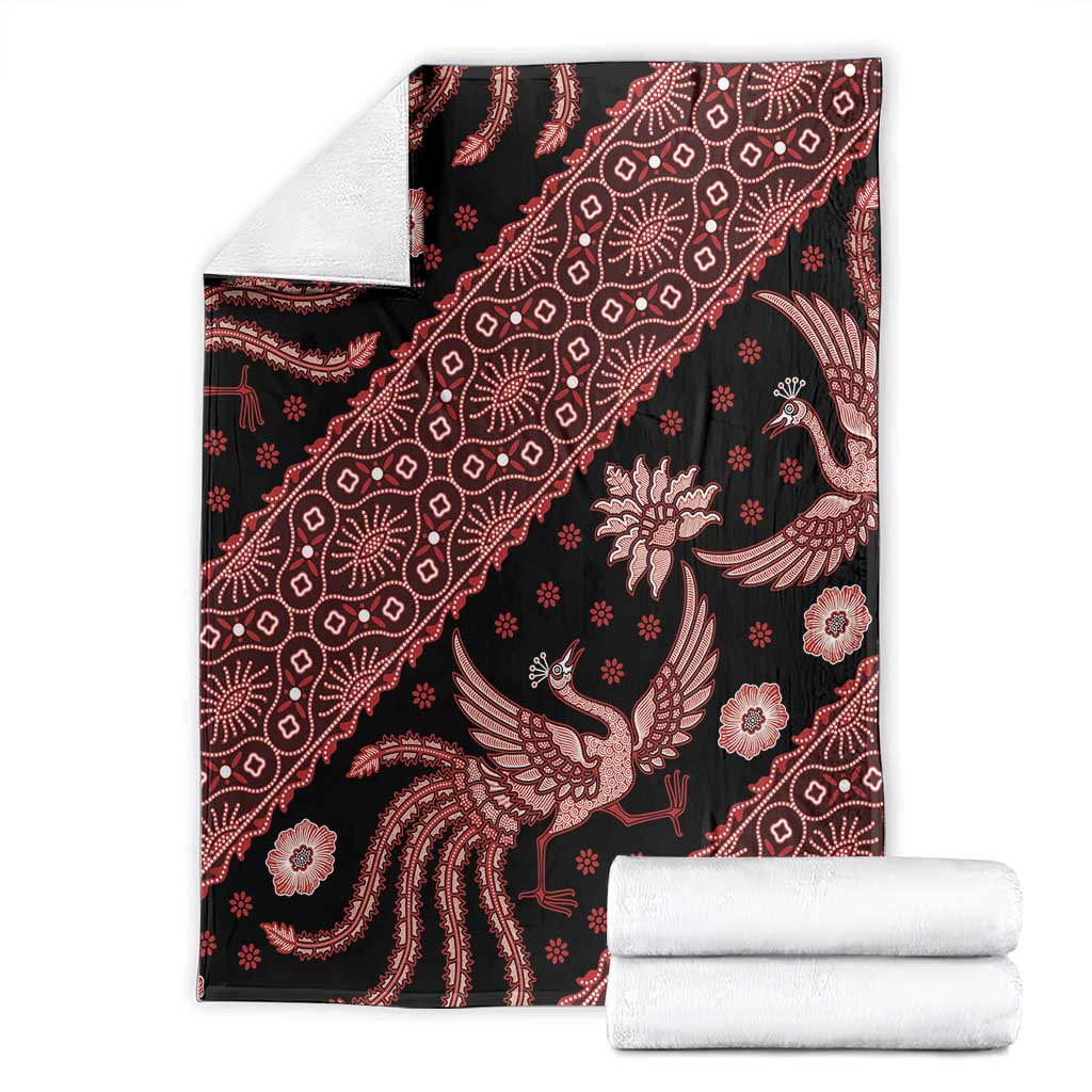 Batik-pattern blanket with dark ground and red bird and floral motifs, with folded towels