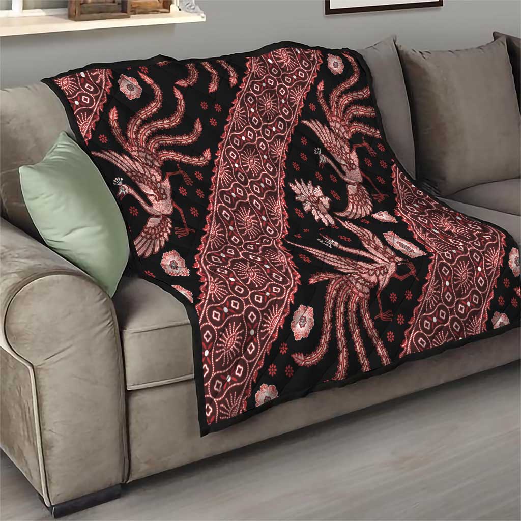 Red and black batik pattern quilt blanket with floral and animal motifs on a sofa