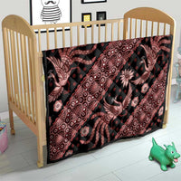 Red and black batik pattern quilt with stylized motifs, draped over a crib