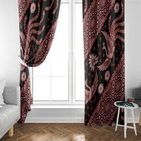 Black window curtains with red batik motifs framing bright door window