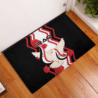 Black rubber doormat with white dove and red zigzag Iraq flag design, entryway view