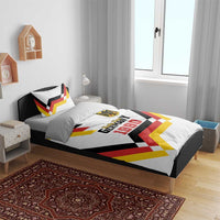 White bedding set on bed with Unity Day 1990 print, shield emblem, and multicolor chevron