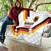 White quilt draped over furniture with Germany 1990 emblem and tricolor V pattern