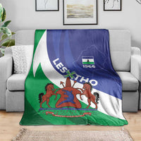 Lesotho-themed blanket with blue, white, and green coat of arms design, laid on couch