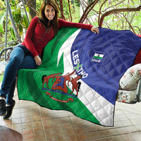 Flag quilt on couch, green-white-blue diagonal stripes with central coat-of-arms and quilt stitching