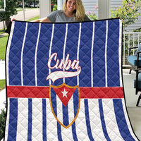 Cuba quilt blanket held outdoors, blue-and-white vertical stripes with red band and Cuban emblem
