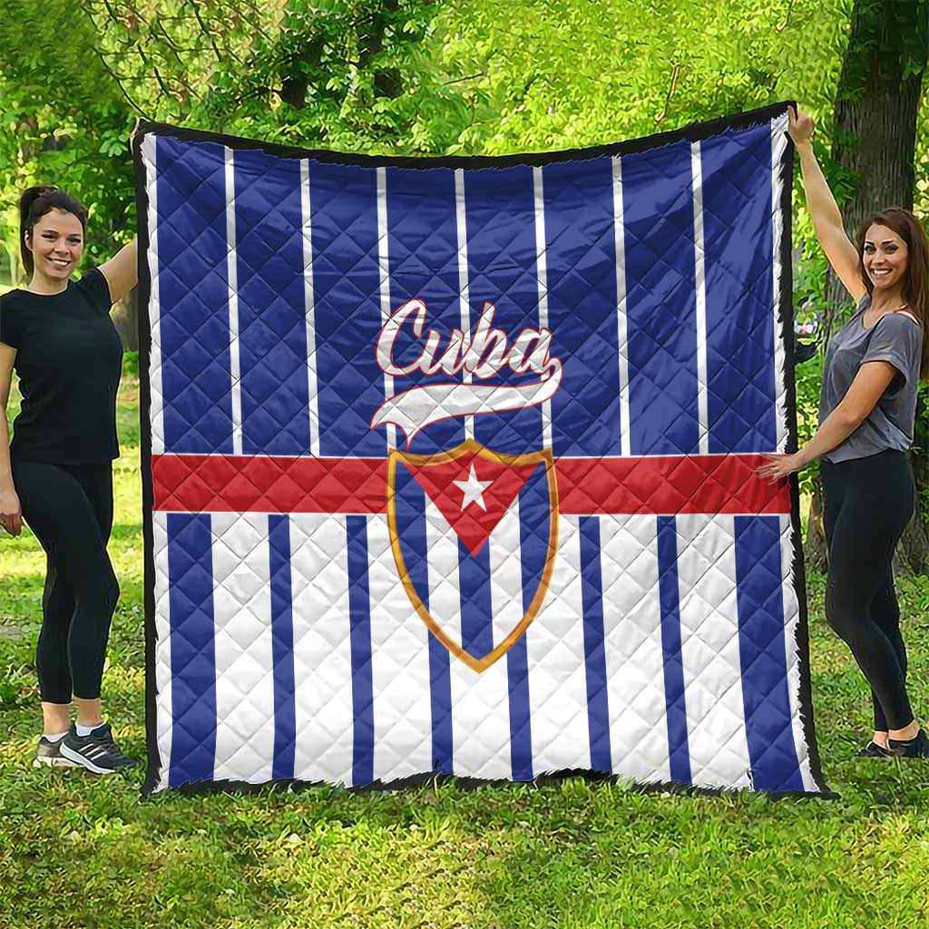 Cuba quilt blanket spread on grass, blue-and-white striped pattern with red band and Cuban crest