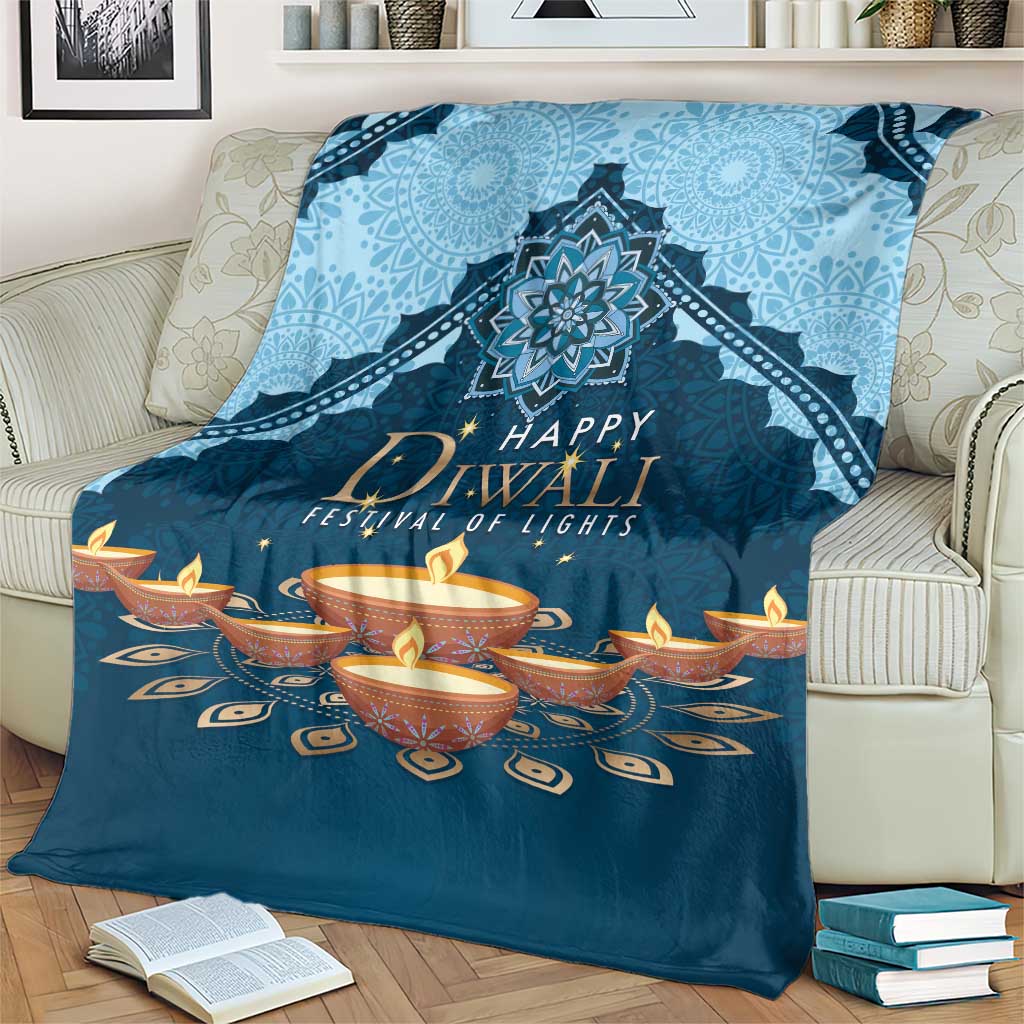 Blue Diwali festival blanket folded on couch with central mandala and diya candles