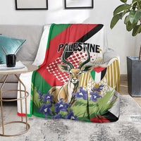 Palestine blanket on floor with gazelle graphic and purple blossoms, red green black white