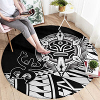 Black round area rug with white tribal mask, hand motifs, and radiating geometric lines