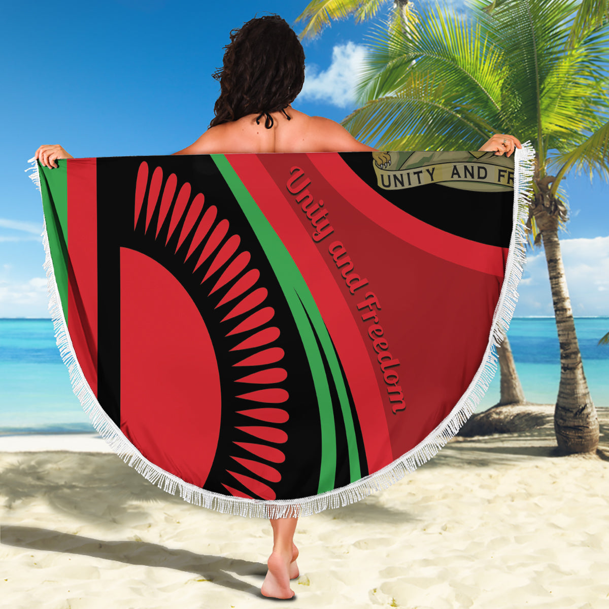 Round beach blanket with Malawi flag-style graphic, white fringe, held outdoors