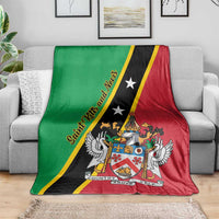 Green, black, and red Saint Kitts and Nevis blanket on sofa, featuring crest, wings, and stars