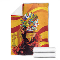 Folded yellow and red flamenco throw blanket with central portrait and emblem; includes rolled towels.