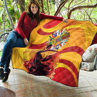 Yellow quilt with red spiral swirls and a central round emblem, laid over couch