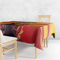 Tablecloth draped over dining table, yellow and red design with dark figure art