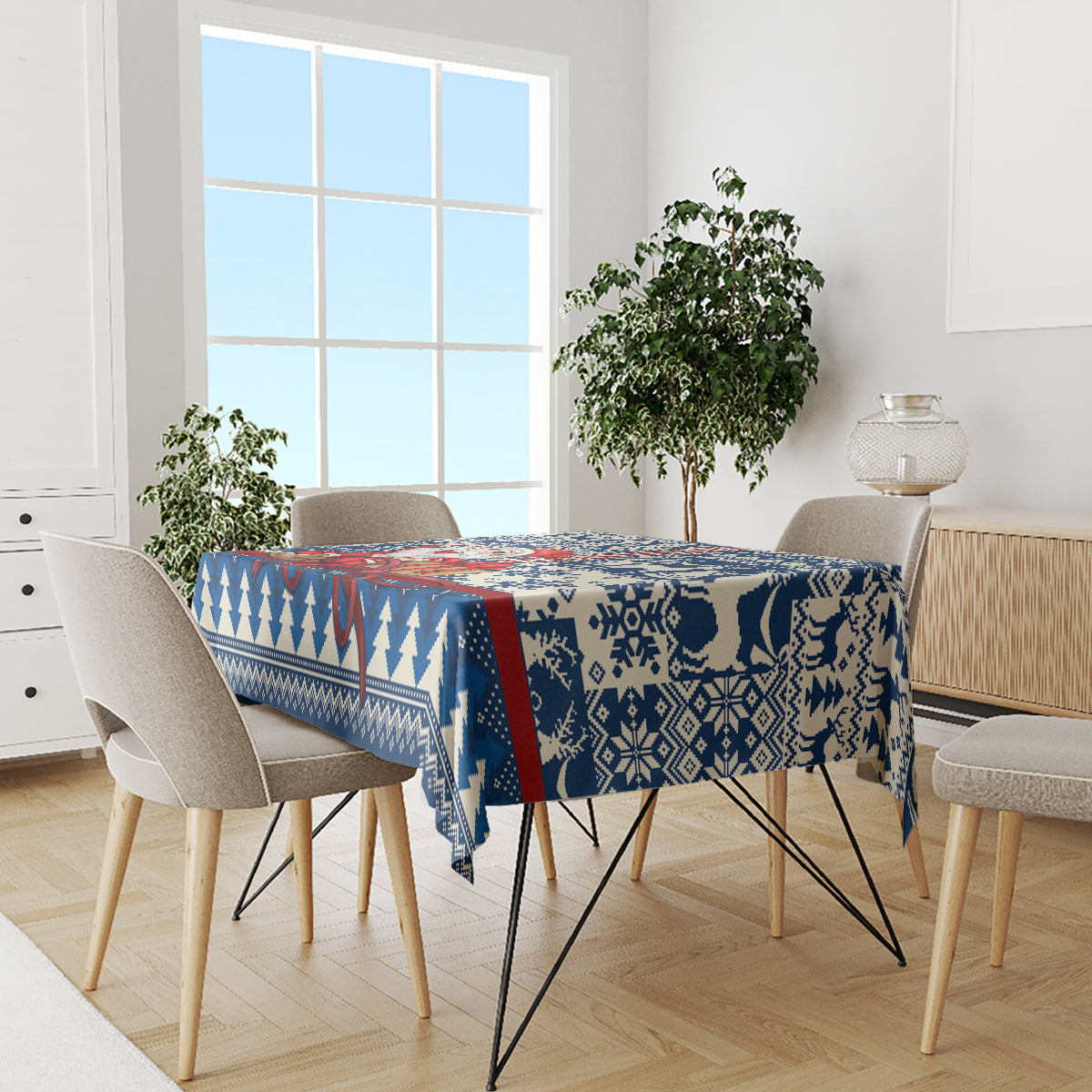 Blue holiday tablecloth with wide snowflake and reindeer pattern over dining table