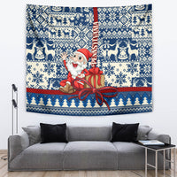 Blue holiday wall tapestry showing Santa with gift box and bow, with reindeer and tree stripe border