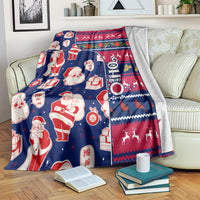 Santa and gift print Christmas blanket draped over couch with red, blue, and festive border