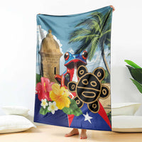 Blue blanket draped over couch showing El Morro tower, coqui frog, palms, flowers and star